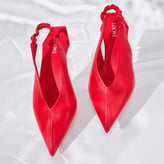 Paires de escarpins ou slingbacks rouges pointus à talon découvert, posés sur un tissu blanc satiné.