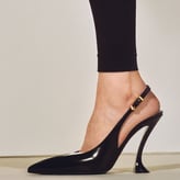 Escarpin noir à talon haut avec bride arrière et détail doré.