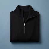 Pull noir soigneusement plié, doté d'un col montant zippé à fermeture métallique.