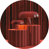 Deux lampes champignon rouges présentées sur des piédestaux cannelés assortis, devant un rideau de velours bordeaux