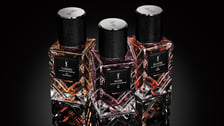 Trois flacons de parfum Yves Saint Laurent de luxe, de la collection Extrait de Parfum, sont présentés sur une surface réfléchissante noire