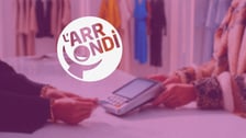 Scène de paiement par carte bancaire sur un terminal de paiement dans un magasin, recouverte d'un filtre violet et d'un logo circulaire blanc affichant l'inscription « L'ARRONDI ».