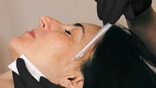 Gros plan sur un soin du visage JetPeel appliqué sur le profil d'une cliente par un professionnel gantage