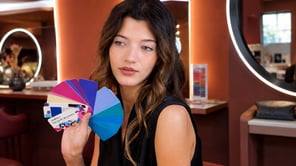 Une femme aux cheveux châtain ondulés tient un éventail de nuances de couleurs vives (rose, violet, bleu). La carte de couleur au premier plan indique "Bright Winter"