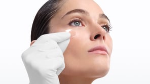 Cette image en gros plan montre une femme vue en contre-plongée, posant sur un fond blanc uni très lumineux.