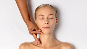 Gros plan d'une femme blonde aux yeux fermés recevant un massage du visage.
