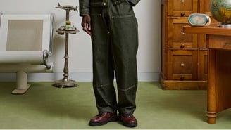 Ensemble de travail en toile denim vert foncé avec coutures contrastées et chaussures de randonnée en cuir bordeaux.
