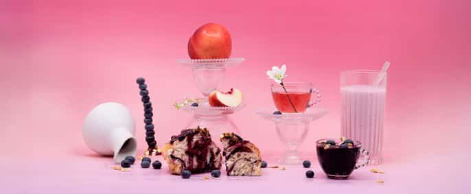 Un plan en studio de nourriture de petit-déjeuner sur un fond rose avec un gâteau au centre.