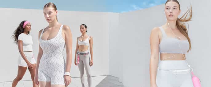 Une photographie de mode présente quatre femmes debout à l'extérieur devant un mur blanc texturé, sous un ciel bleu clair