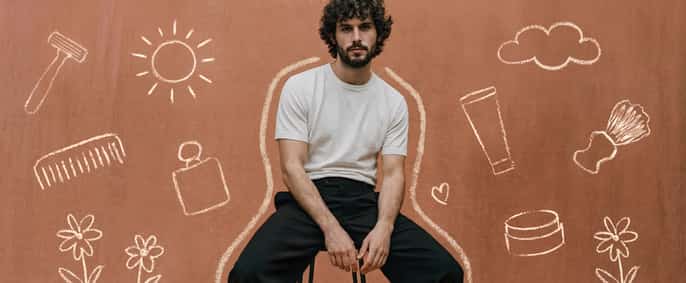 Un portrait de face à la taille d'un homme barbu aux cheveux bouclés, assis sur un tabouret.